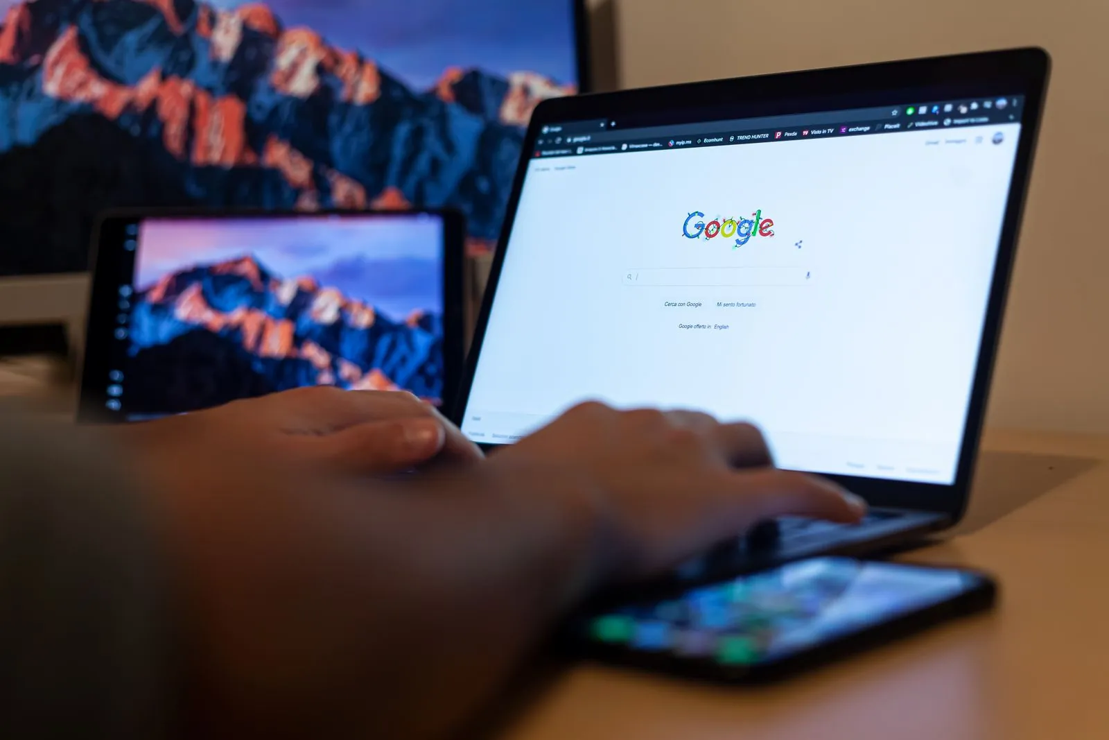 Dizüstü bilgisayarda Google arama sayfası açıkken klavyede yazan el